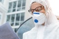 Portrait of tired exhausted female doctor, scientist or nurse wearing face mask and biological hazmat ppe suit reading who Royalty Free Stock Photo