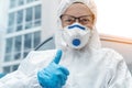 Portrait of tired exhausted female doctor, scientist or nurse wearing face mask and biological hazmat ppe suit showing comfidence Royalty Free Stock Photo