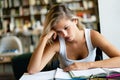 Portrait of a tired female student studying with books at the library