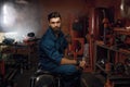 Portrait of tired but happy workman sitting on repaired motorcycle in workshop