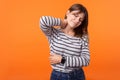 Portrait of tired sick woman with brown hair in long sleeve striped shirt. indoor studio shot isolated on orange background