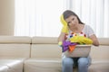 Portrait of tired woman with basket of cleaning supplies sitting on sofa at home Royalty Free Stock Photo