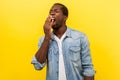 Portrait of tired worker, exhausted man yawning covering mouth with hand. indoor studio shot isolated on yellow background Royalty Free Stock Photo