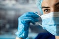 Portrait of tired young doctor taking off medical face mask after a shift in clinic Royalty Free Stock Photo