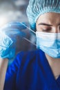 Portrait of tired young doctor taking off medical face mask after a shift in clinic Royalty Free Stock Photo