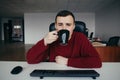 Portrait of a tired young office worker drinking coffee at work. The situation in the office Royalty Free Stock Photo