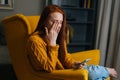 Portrait of tired young woman having blurry vision is rubbing and squinting eyes while typing using smartphone. Royalty Free Stock Photo