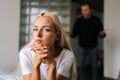 Portrait of tired young woman sadness looking at camera sitting on bed on background of aggressive husband shouting on Royalty Free Stock Photo