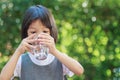 Portrait of a 4 to 6 year old Thai kid Asian girl with cute face holding a glass of water. She is drinking water to refresh her Royalty Free Stock Photo