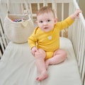 Portrait of a toddler baby boy sitting in a crib, yellow clothes. Kid in his bed, age eight months Royalty Free Stock Photo