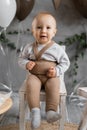 Portrait of a toddler boy on his first birthday, cute baby on a chair posing, background decoration. Royalty Free Stock Photo