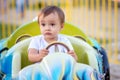 Portrait of toddler boy sitting on little car on merry-go-round in theme park and holding steering wheel. Future racing driver Royalty Free Stock Photo