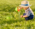 Toddler child outdoors. One year old baby boy wearing straw hat using watering can Royalty Free Stock Photo