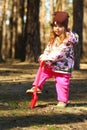 Portrait of a toddler girl digging the forest ground with a toy red shovel