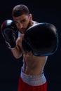 Portrait of tough male boxer posing in boxing stance against black background.