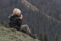 Portrait of tourist boy in mountains resting on hillside with cup of tea. Hiking with child in the fall. Active recreation