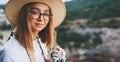 Portrait tourist girl in summer hat hold in hands retro camera and takes photos on backdrop of mountains landscape