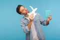 Portrait of tourist man in worker denim shirt playing with paper plane, holding passport and dreaming of vacation Royalty Free Stock Photo