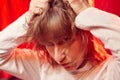 Portrait of tousled disheveled middle-aged woman looking like a madwoman on red background in studio. Actress during the