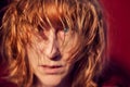 Portrait of tousled disheveled middle-aged woman looking like a madwoman on red background in studio. Actress during the