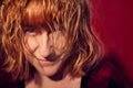 Portrait of tousled disheveled middle-aged woman looking like a madwoman on red background in studio. Actress during the