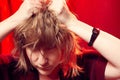 Portrait of tousled disheveled middle-aged woman looking like a madwoman on red background in studio. Actress during the