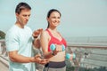 Portrait of trainer with female athlete exercising with dumbbells on the city bridge in the morning