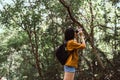 Portrait of travel young asian woman using binoculars in forest,Enjoying with bird watching