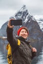 Portrait traveler man taking self-portrait a photo with a smartphone. Tourist in a yellow backpack standing on a Royalty Free Stock Photo