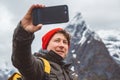 Portrait traveler man taking self-portrait a photo with a smartphone. Tourist in a yellow backpack standing on a Royalty Free Stock Photo