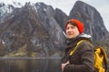 Portrait traveler man with a yellow backpack wearing a red hat on the shore on the background of mountain and lake Royalty Free Stock Photo