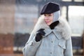 Portrait trendy mature woman Stands outside in snow, wears fashionable winter multilayer outfit, grey coat with fur