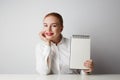 Portrait of trendy redhead woman posing in shirt holding empty notepad over white background. Royalty Free Stock Photo
