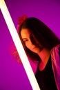 Portrait trendy young female dancer posing in the studio on a colorful background with neon lighting tube. Fashion Royalty Free Stock Photo