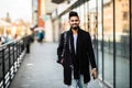 Portrait of a trendy young man with backpack walking in the city street Royalty Free Stock Photo