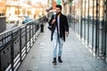 Portrait of a trendy young man with backpack walking in the city street Royalty Free Stock Photo