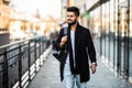 Portrait of a trendy young man with backpack walking in the city street Royalty Free Stock Photo