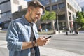 Portrait of a trendy young man in the city walking with his phone Royalty Free Stock Photo