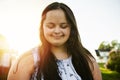 A Portrait of trisomie 21 adult girl outside at sunset