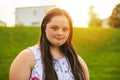 A Portrait of trisomie 21 adult girl outside at sunset