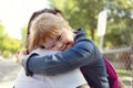 A portrait of trisomie 21 child girl outside hugging his mother on a school playground