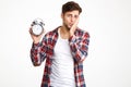 Portrait of a troubled man holding alarm clock