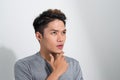 Portrait of troubled young asian guy trying think up plan or idea, standing in thoughtful pose with hand on chin