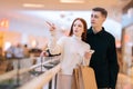Portrait of troubled young couple looking for store in shopping mall centre browsing app on mobile phone. Royalty Free Stock Photo