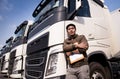 Portrait of Truck driver holding clipboard standing with modern semi truck. Royalty Free Stock Photo