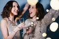 Twin sisters in shiny evening dresses celebrate with glasses of sparkling wine Royalty Free Stock Photo