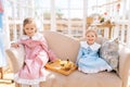 Portrait of two adorable little children sisters in beautiful dress playing with little yellow ducklings in summer Royalty Free Stock Photo