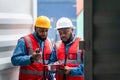 Portrait of Two African Engineer or foreman wears PPE checking container storage with cargo container background at sunset.