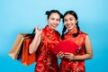 Portrait of two Asian women wearing cheongsams on Chinese New Year holding a red envelope protruding front camera The other hand Royalty Free Stock Photo