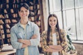 Portrait of two attractive cheerful smart friends learners folded arms visiting public library at loft industrial